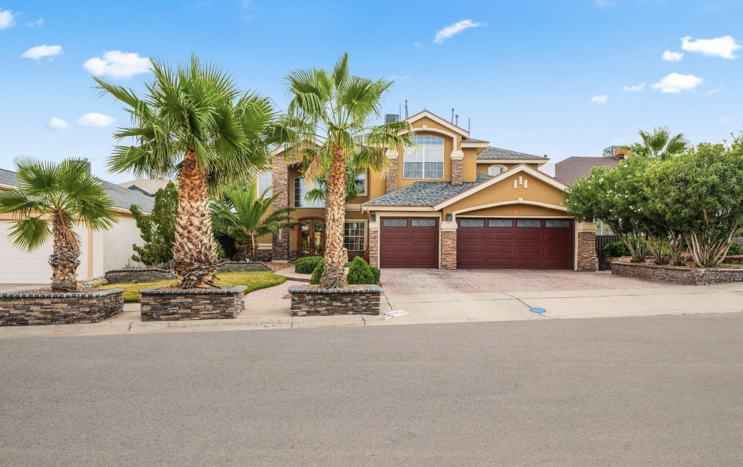 Two-story East El Paso home with palm trees and stone planters